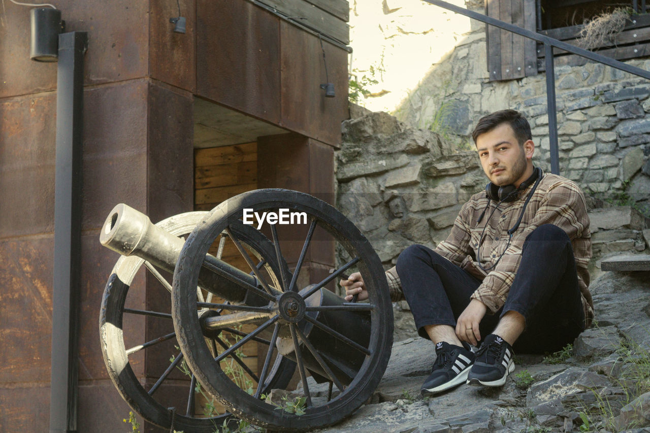 FULL LENGTH PORTRAIT OF YOUNG MAN SITTING ON BICYCLE