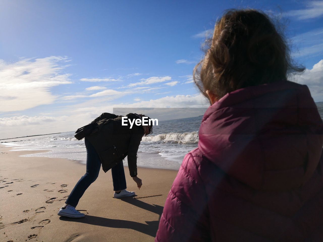 REAR VIEW OF WOMAN WITH DOG ON BEACH