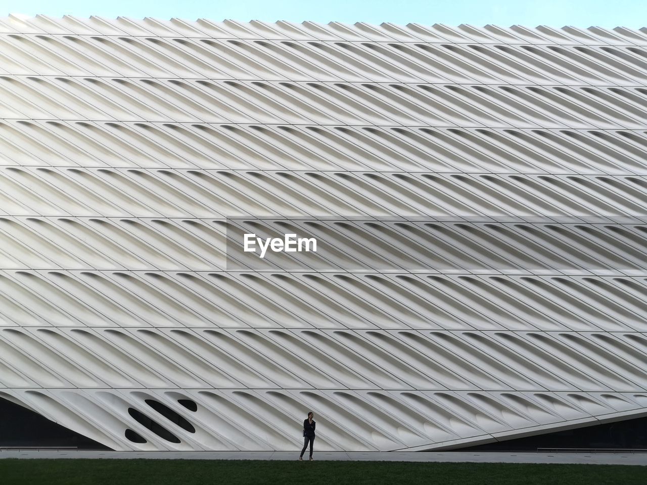 LOW ANGLE VIEW OF MAN WALKING IN CITY AGAINST SKY