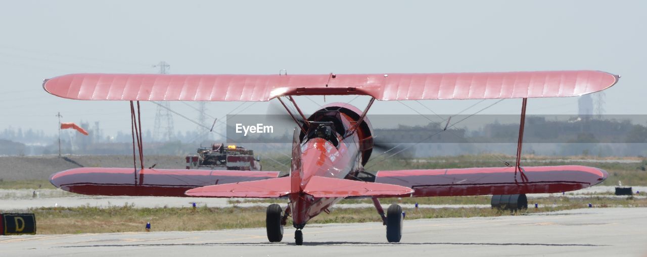 MAN FLYING AIRPLANE AT AIRPORT RUNWAY AGAINST SKY