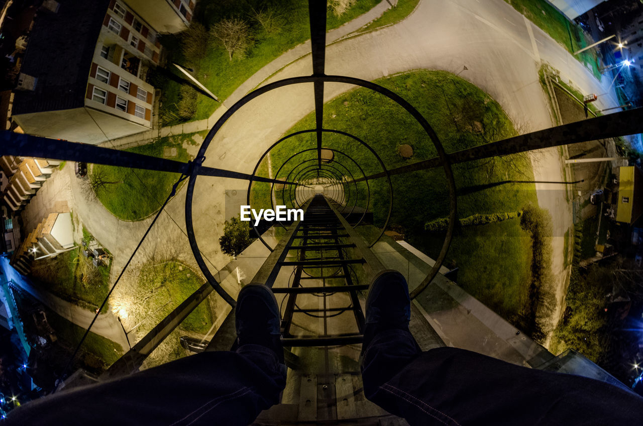 Low section of man standing on metallic ladder at night