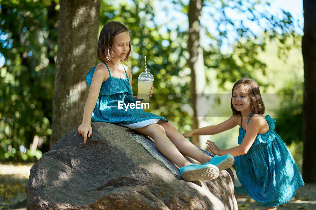 Two little girls drinking lemonade in park