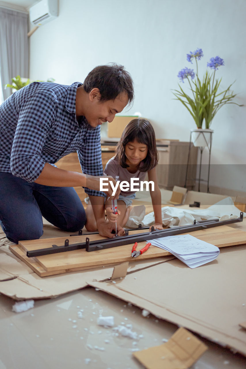 Happy man with daughter installing furniture at home