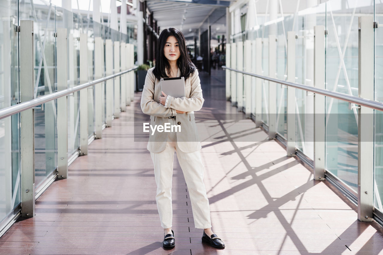 Portrait of beautiful chinese business woman holding tablet in building office. technology