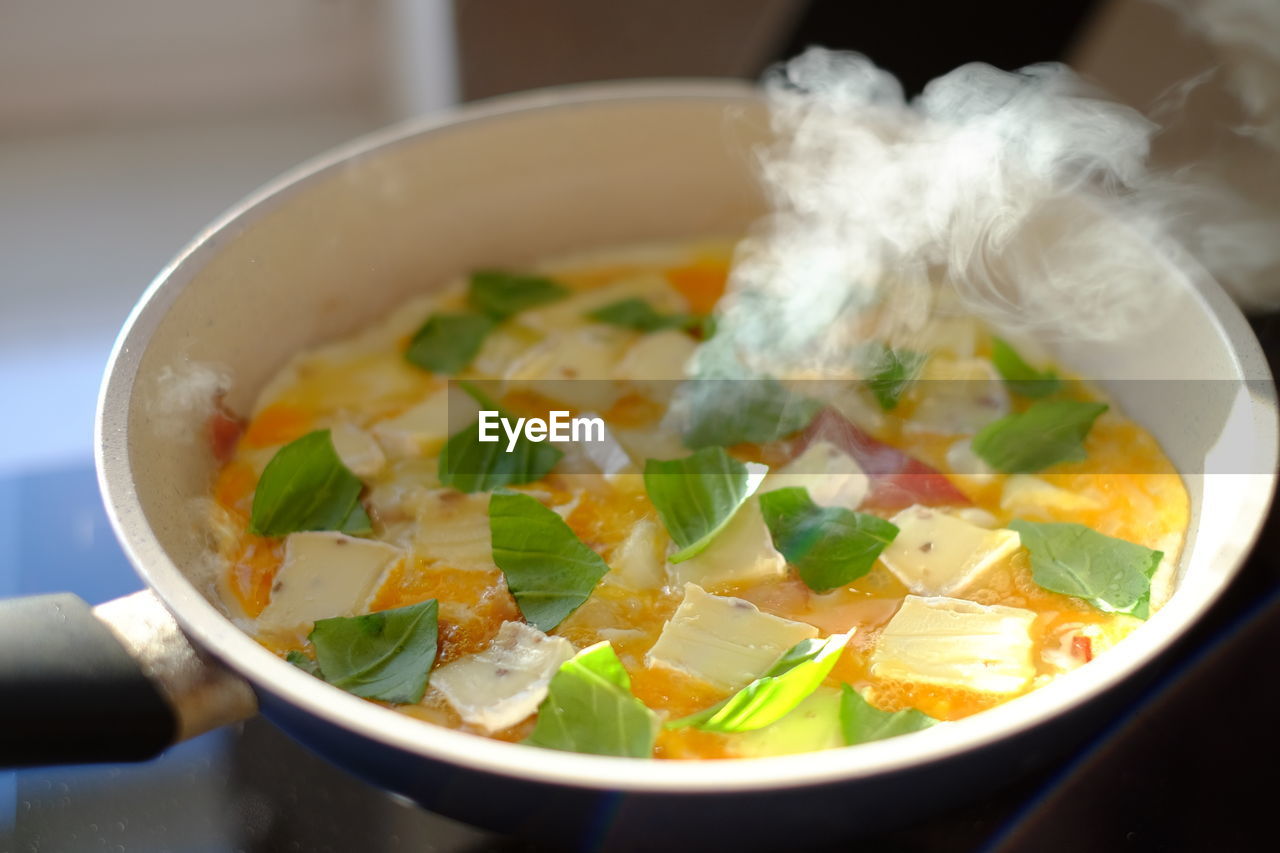 Close-up of eggs with cheese and basil on pan