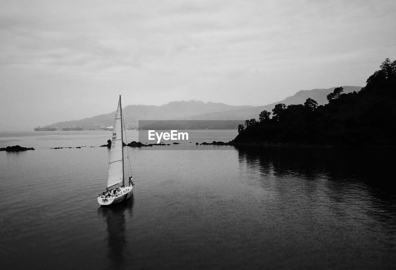 BOAT MOORED IN LAKE AGAINST SKY