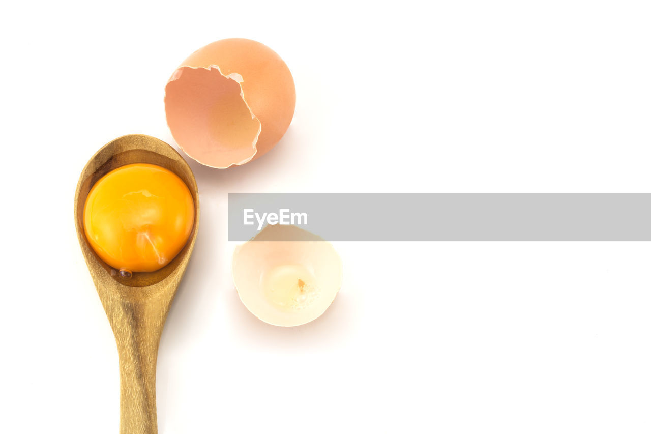 Close-up of egg on spoon against white background