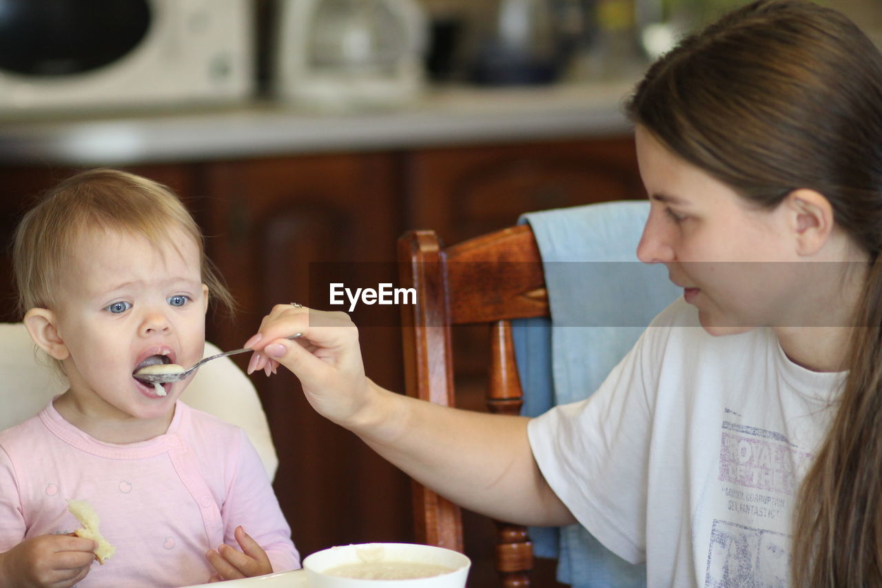 PORTRAIT OF MOTHER AND GIRL SITTING ON TABLE AT CAFE