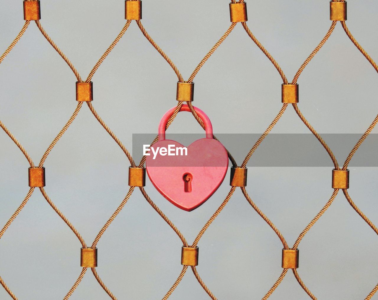 Close-up of heart shape on metal fence against sky