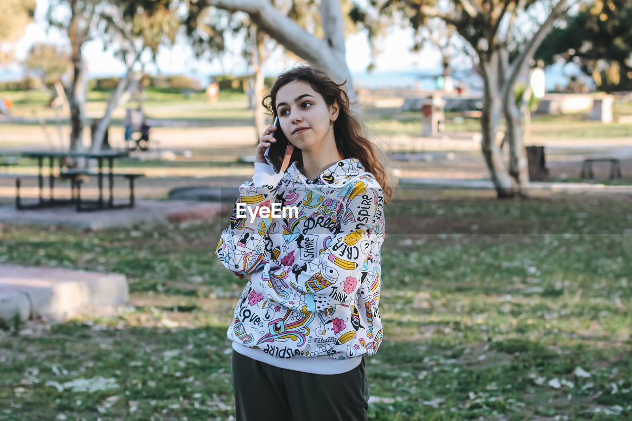 Teenager girl talking on phone at park