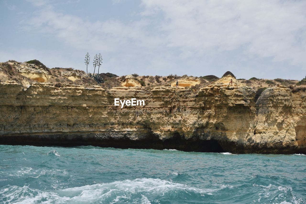 Scenic view of sea by cliff against sky