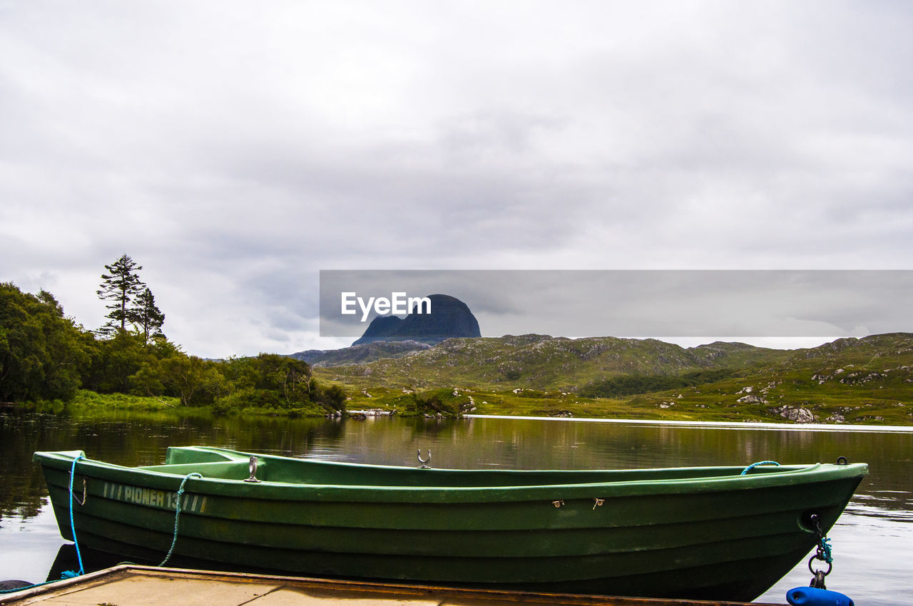 BOAT MOORED ON SHORE AGAINST SKY