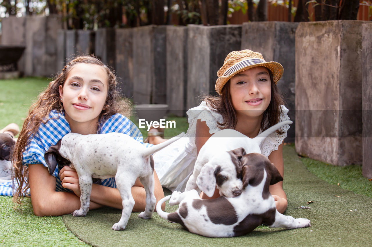 Beautiful young girls having fun with their small french braque puppies