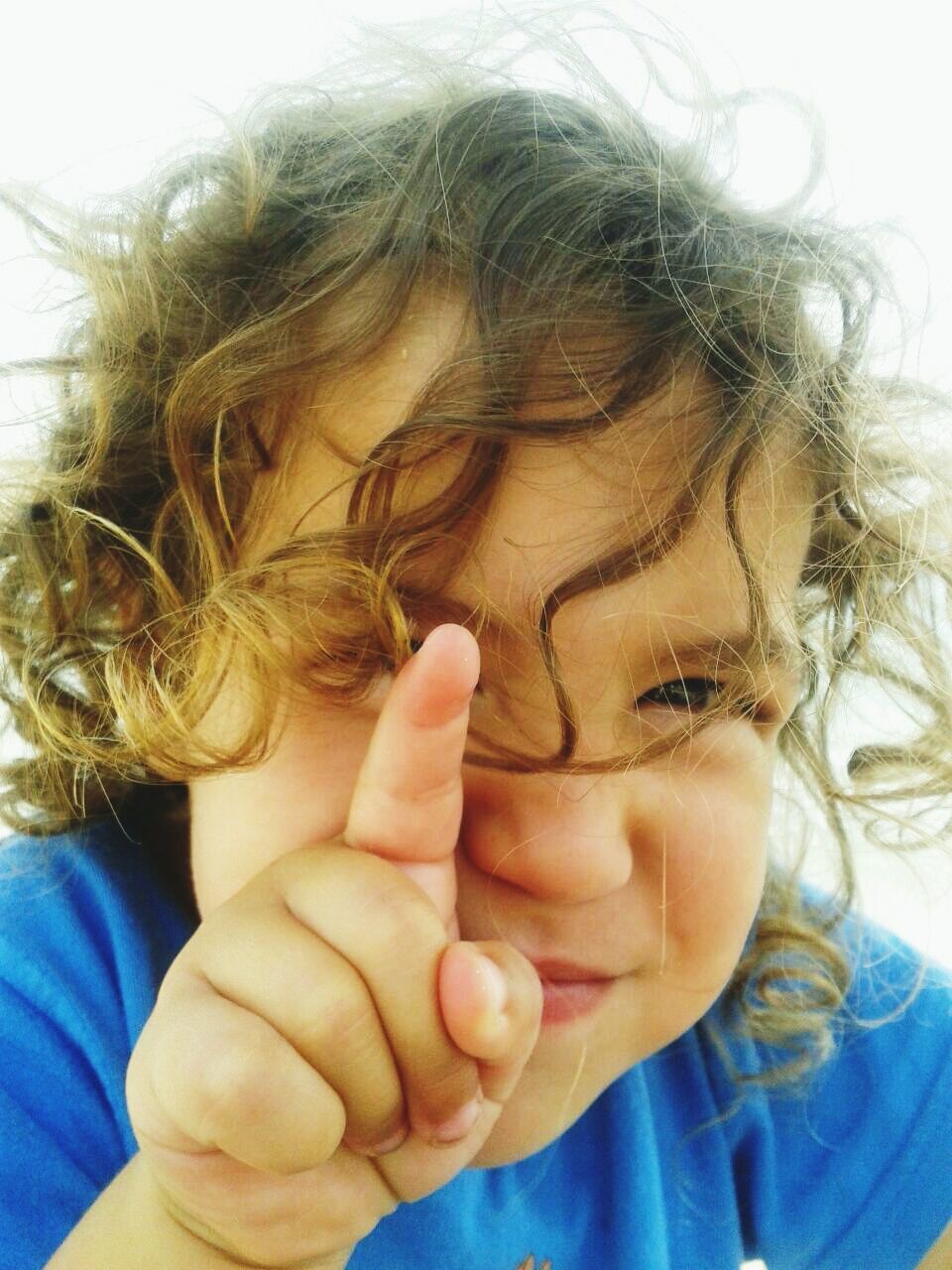 Close-up portrait of girl pointing at beach against sky