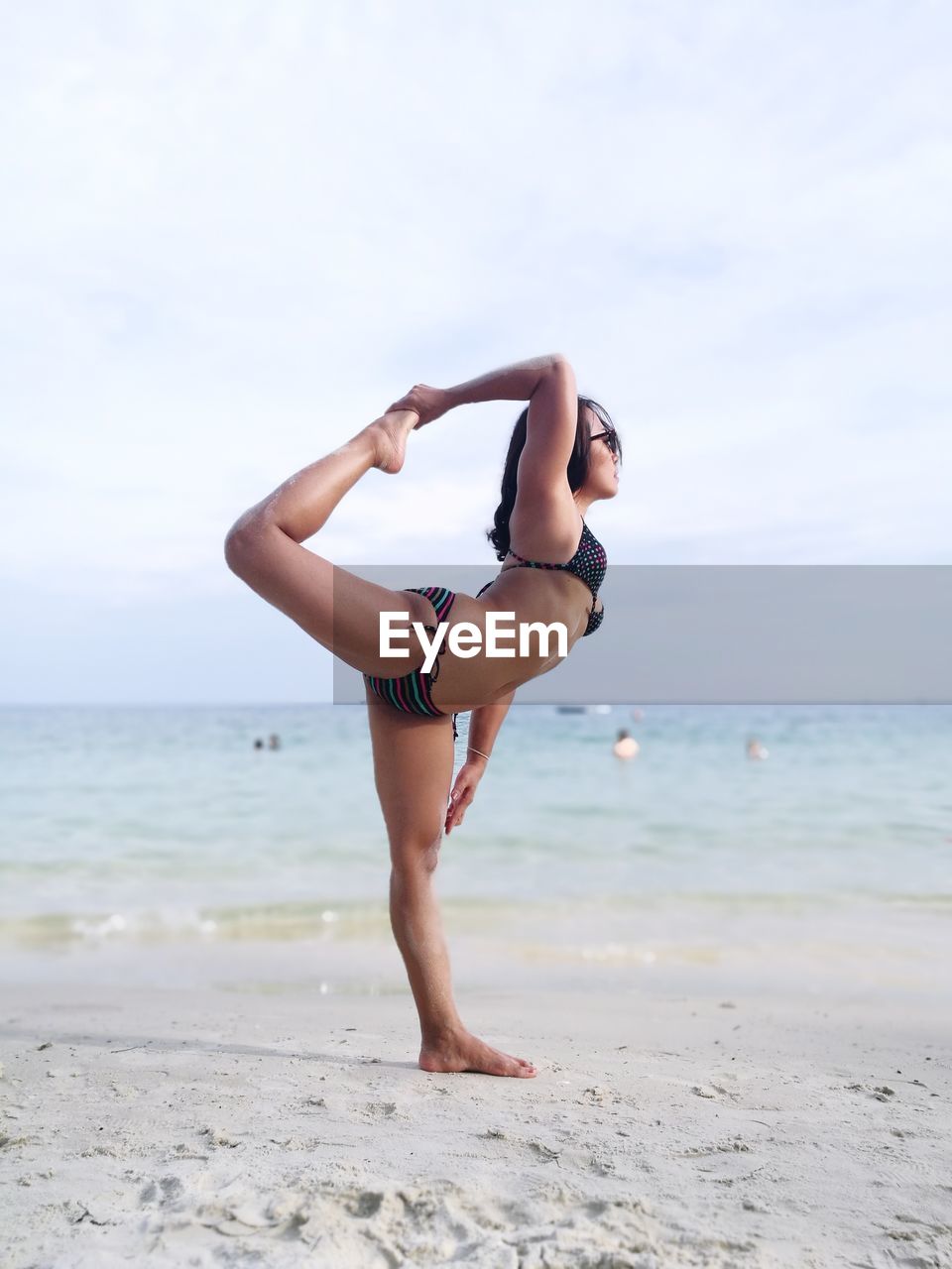 Woman in bikini doing yoga at beach