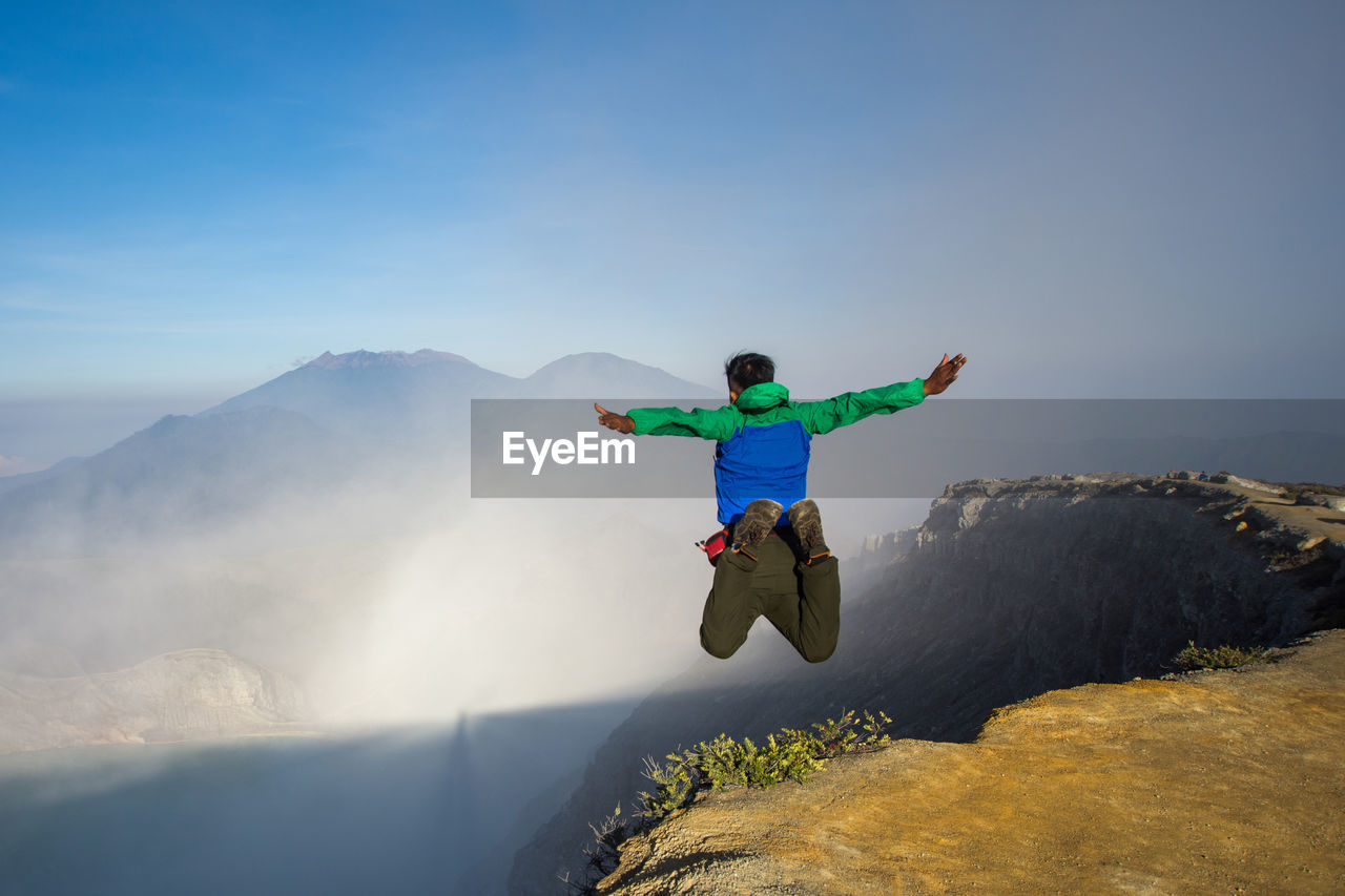 MAN JUMPING AGAINST MOUNTAIN