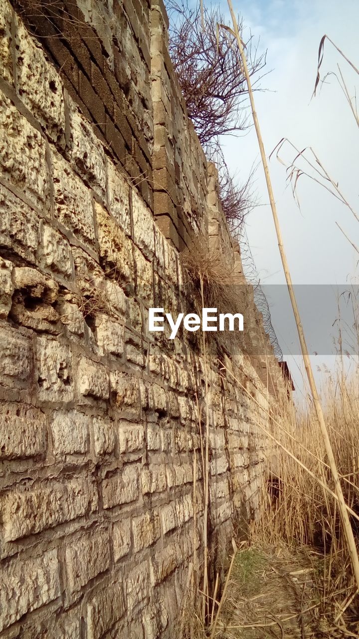 LOW ANGLE VIEW OF STONE WALL ON FIELD