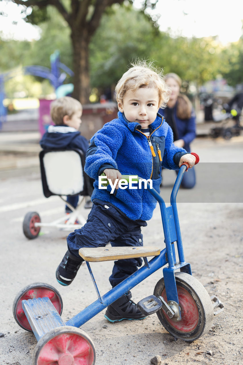 Portrait of boy playing with tricycle on playground