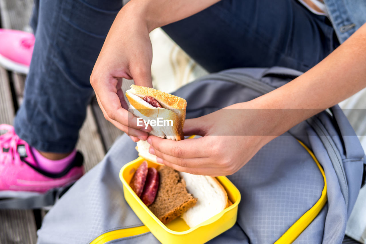 Close-up hands holding sandwich lunchbox backpack