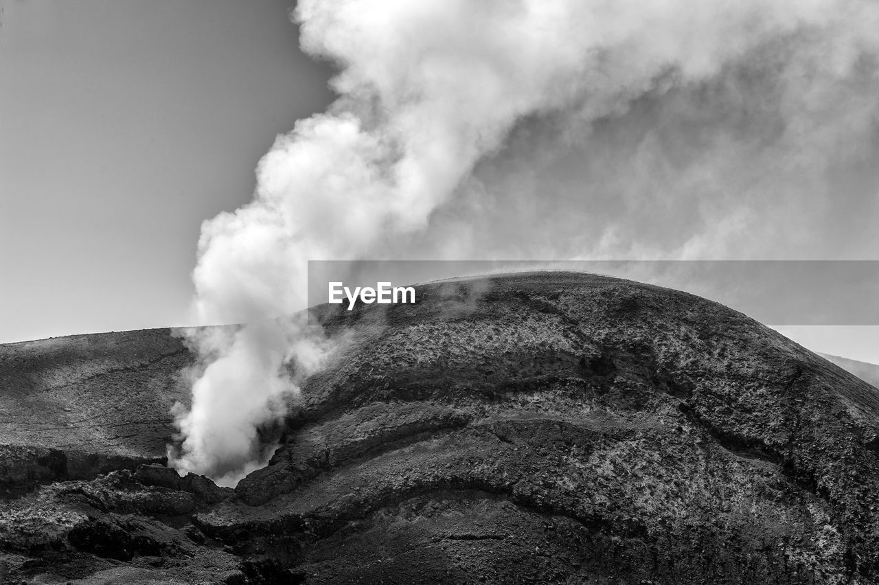 Smoke emitting from volcanic mountain against sky