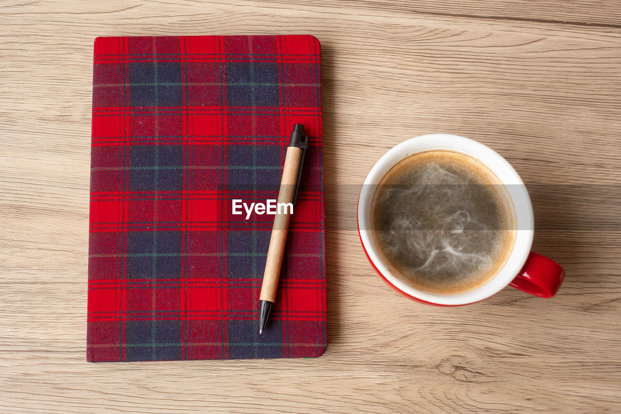 HIGH ANGLE VIEW OF COFFEE CUP AND RED ON TABLE