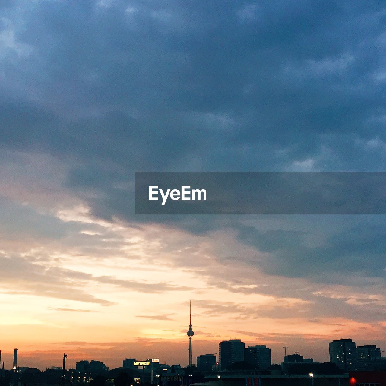 Fernsehturm with city against cloudy sky during sunset