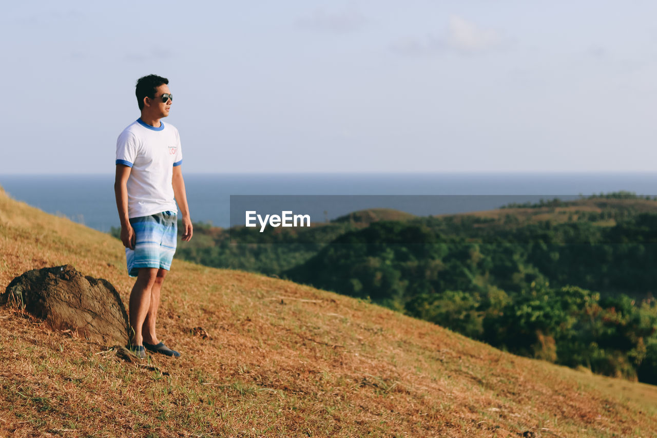 Full length of young man standing on land against sky