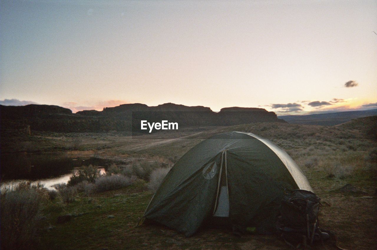 TENT ON FIELD AGAINST SKY DURING SUNSET