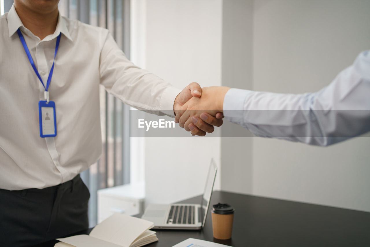 midsection of businessman giving handshake