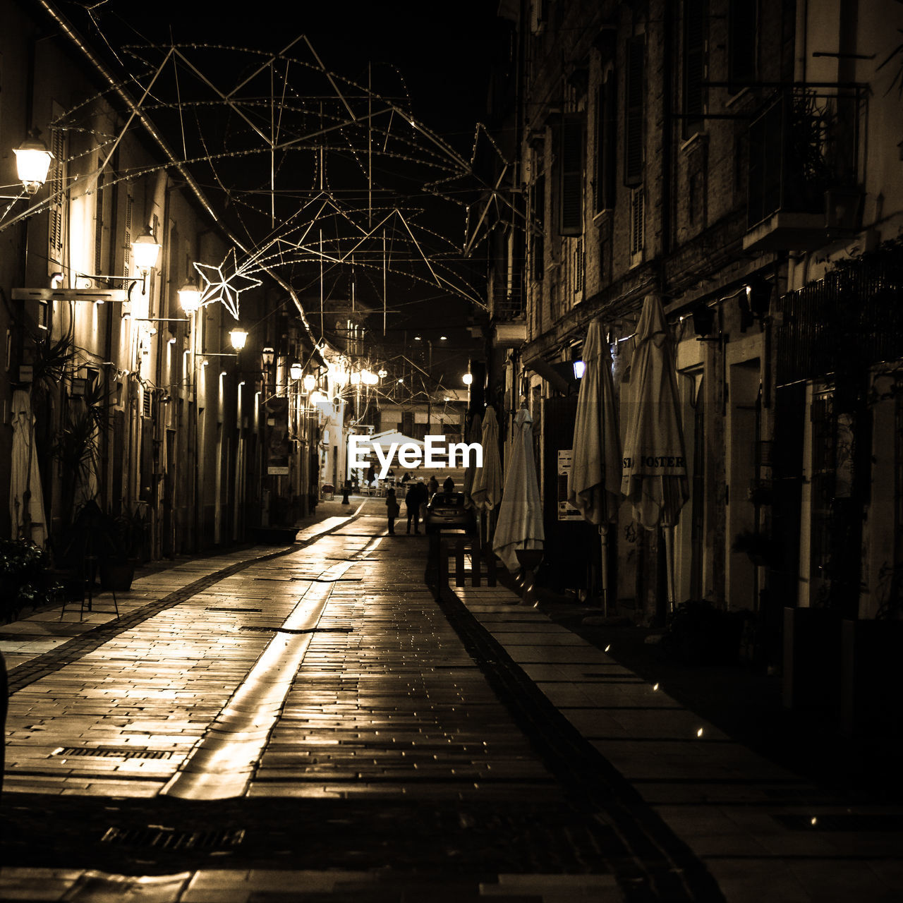 STREET AMIDST ILLUMINATED BUILDINGS AT NIGHT