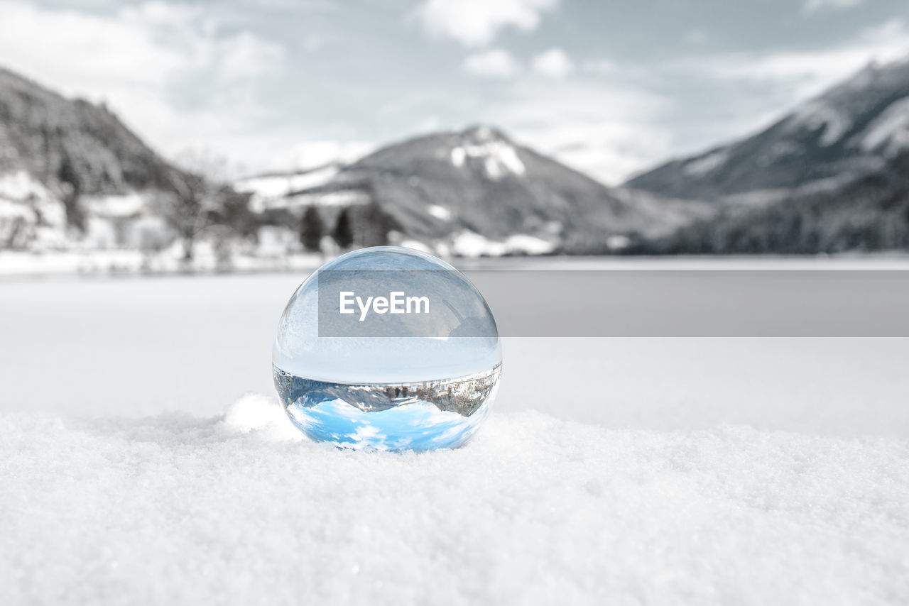 CLOSE-UP OF CRYSTAL BALL ON SNOW COVERED MOUNTAIN