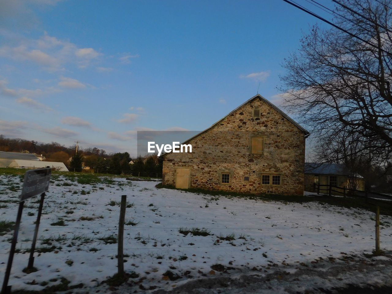 HOUSE ON SNOW COVERED FIELD AGAINST SKY