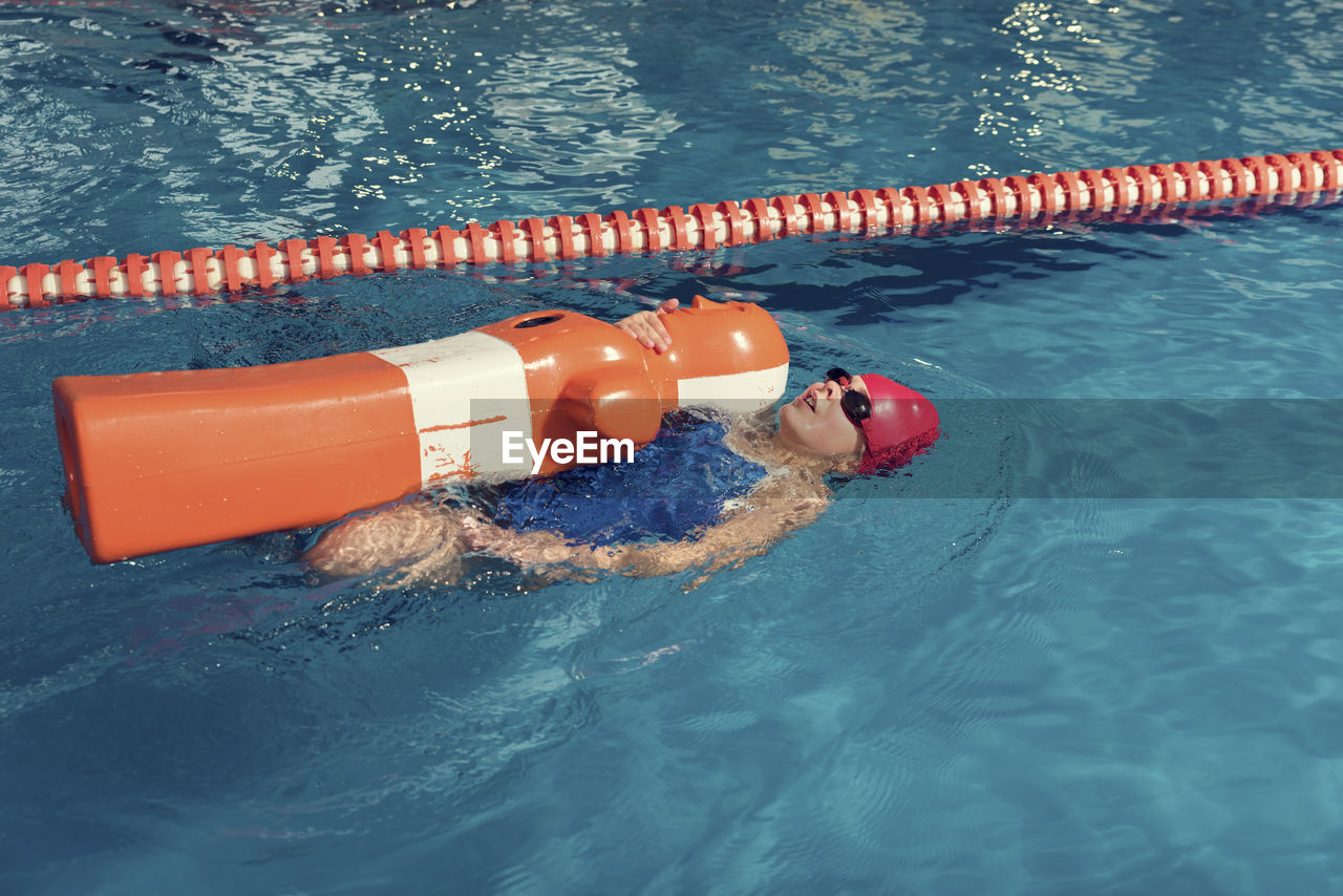 High angle view of girl swimming with dummy in pool