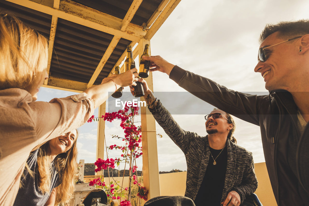 Cheerful friends toasting drinks at balcony