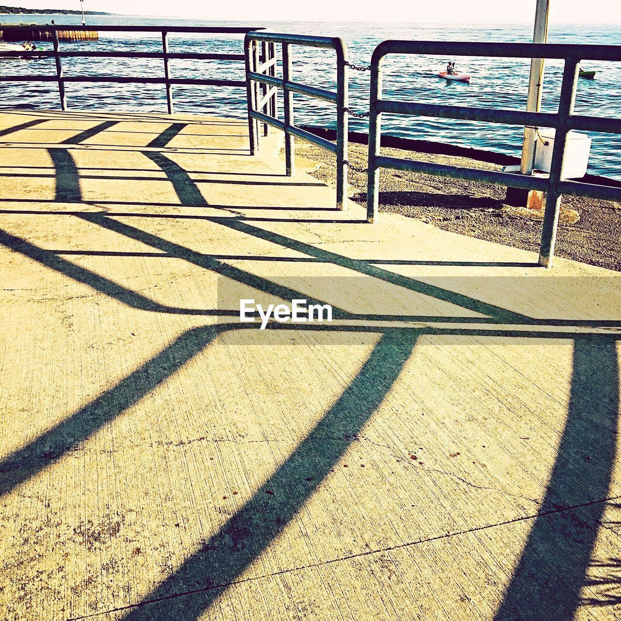 Shadow of railings on pier against lake michigan