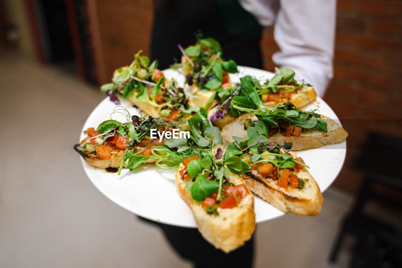 Catering food at the party. catering service. the waiter holds a plate with bruschetta.