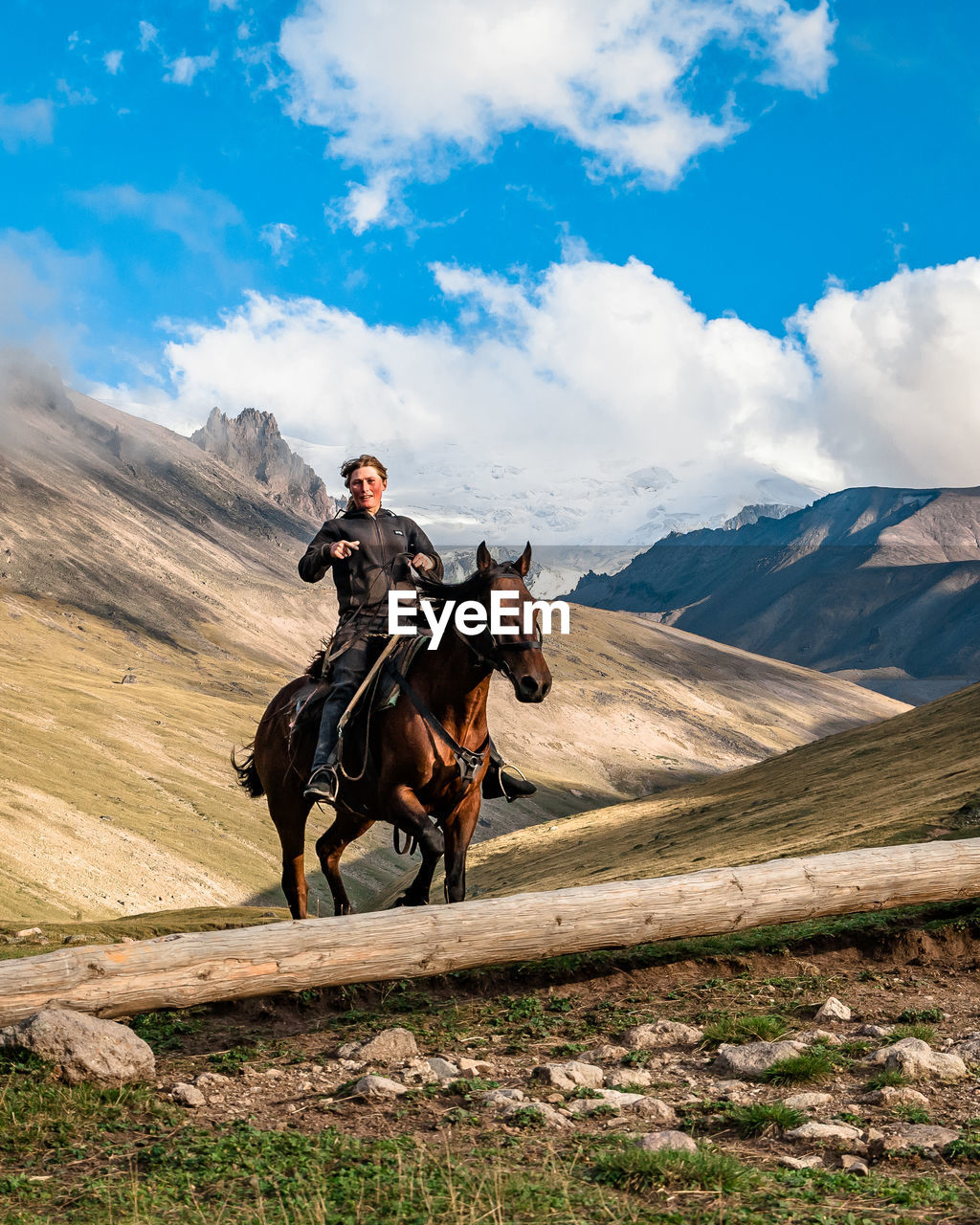 Rider caucasian girl on a horse gallops through a mountain valley