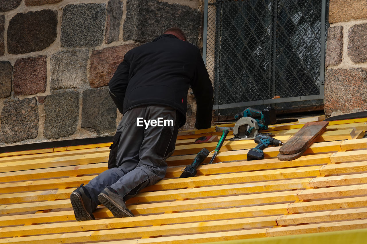 REAR VIEW OF MAN WORKING AT STAIRCASE