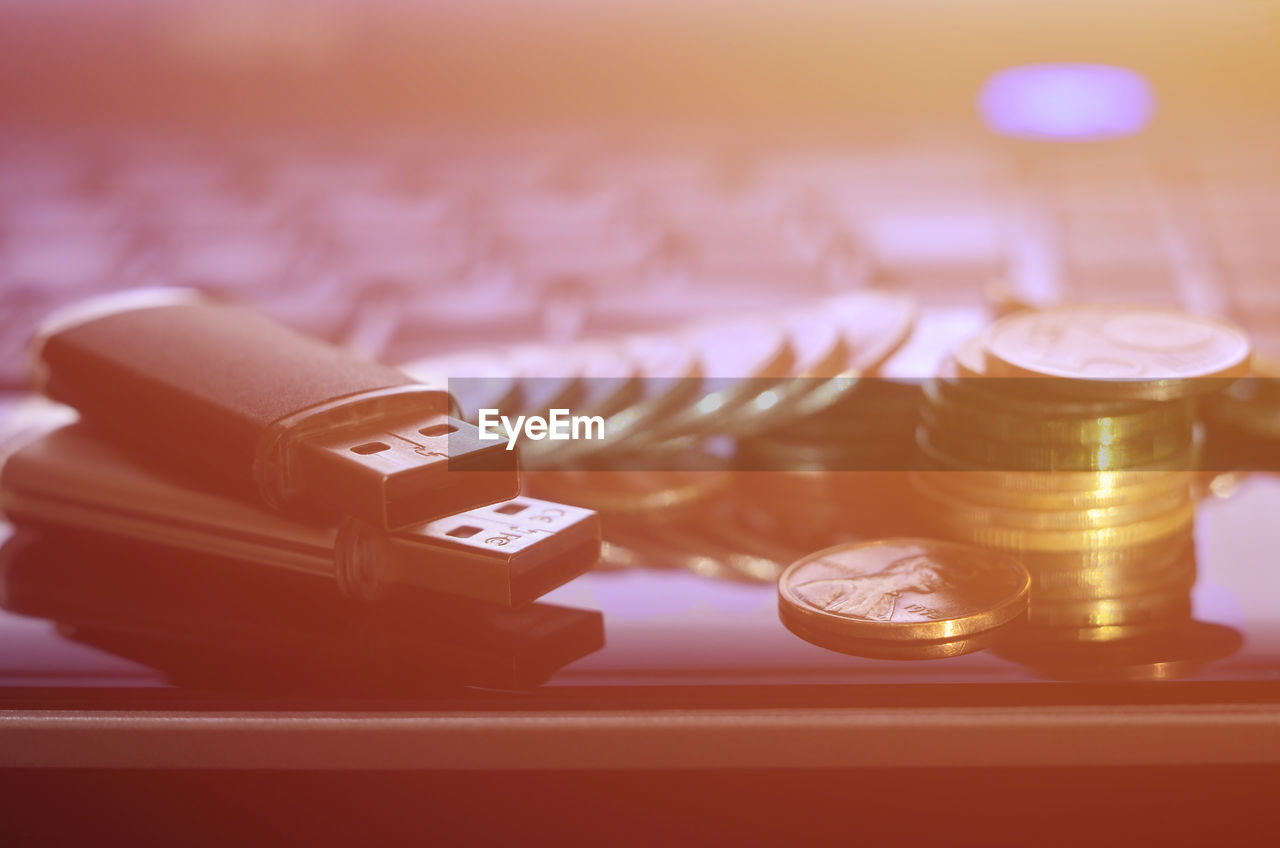 Close-up of coins and usb stick on laptop