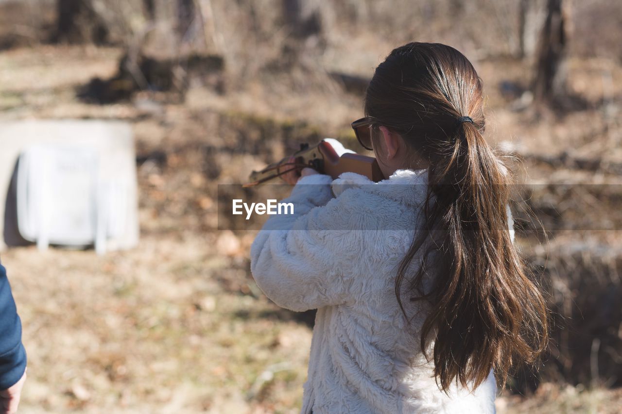 Rear view of woman aiming rifle