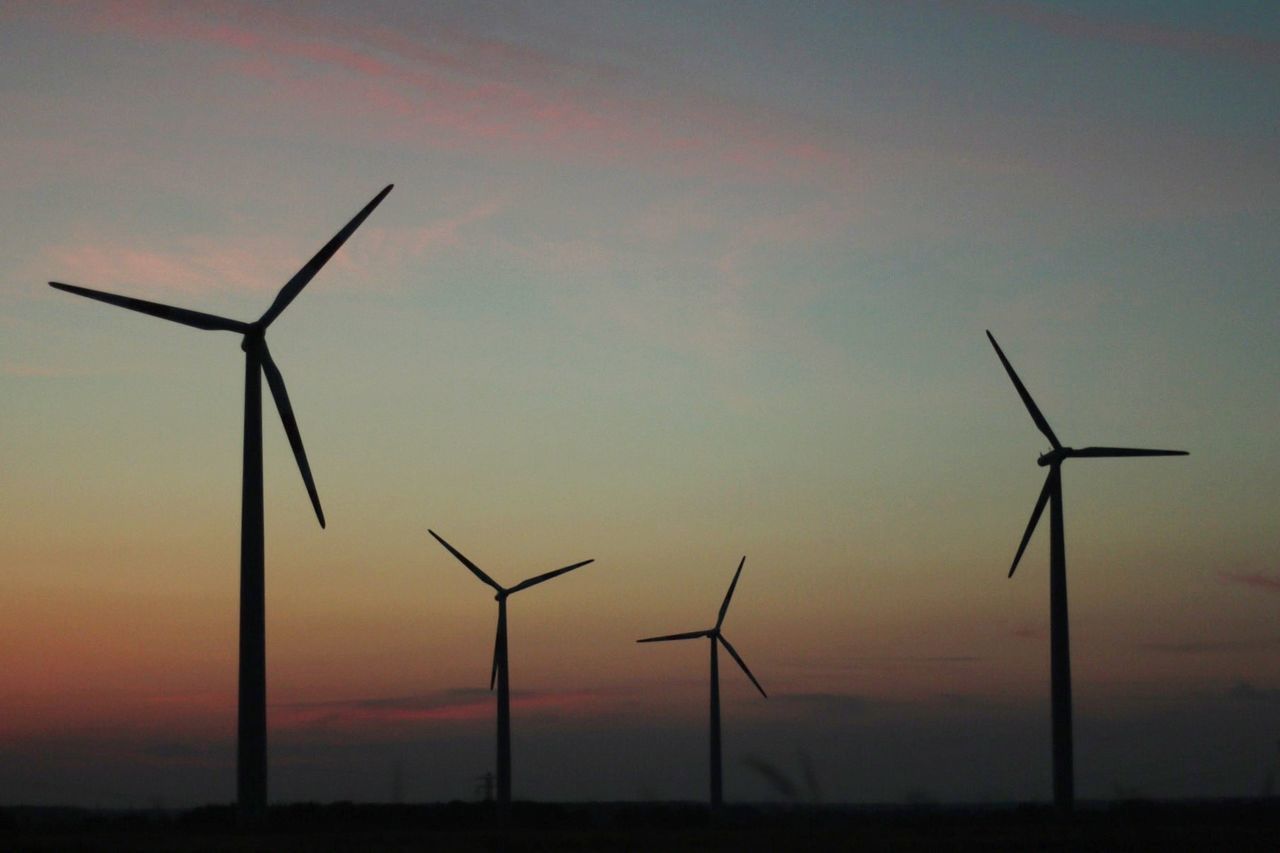 Silhouette windmills against sky during sunset