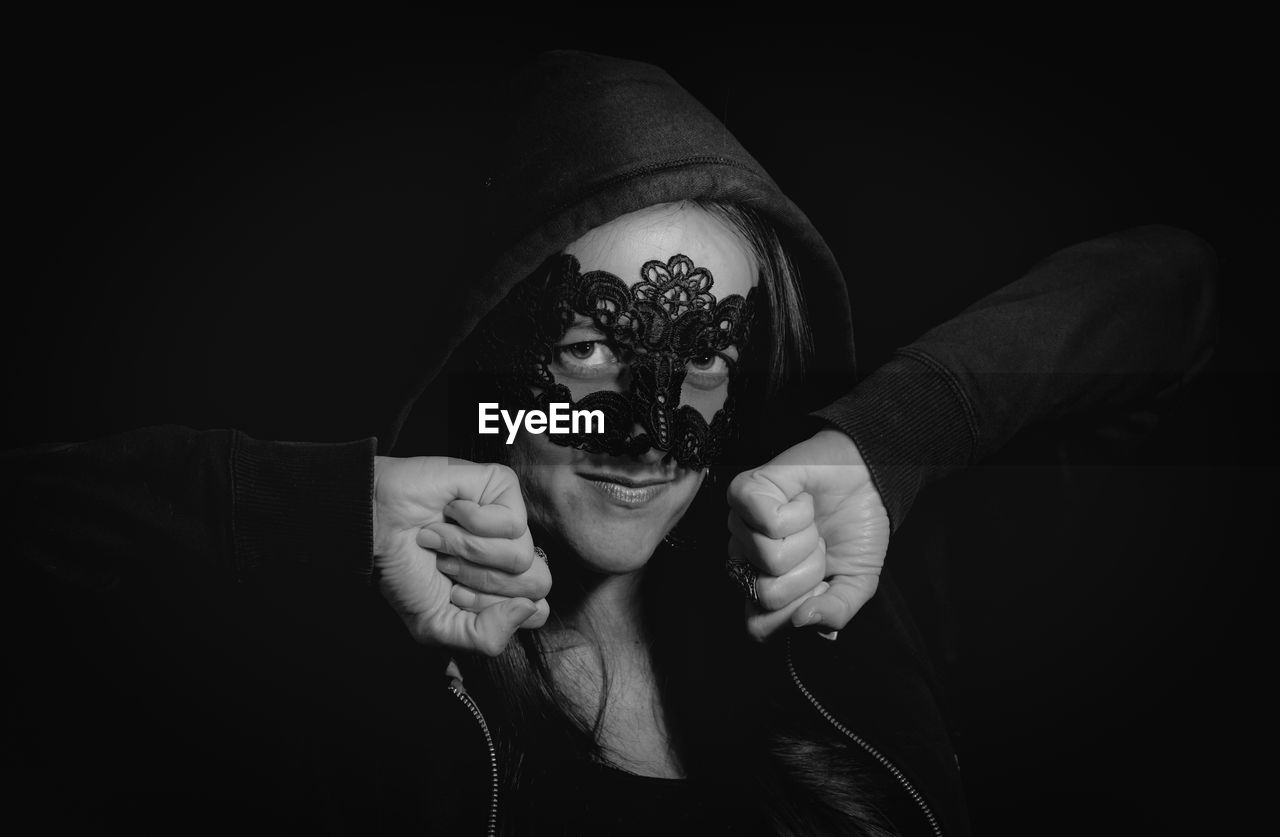 Portrait of woman wearing eye mask against black background