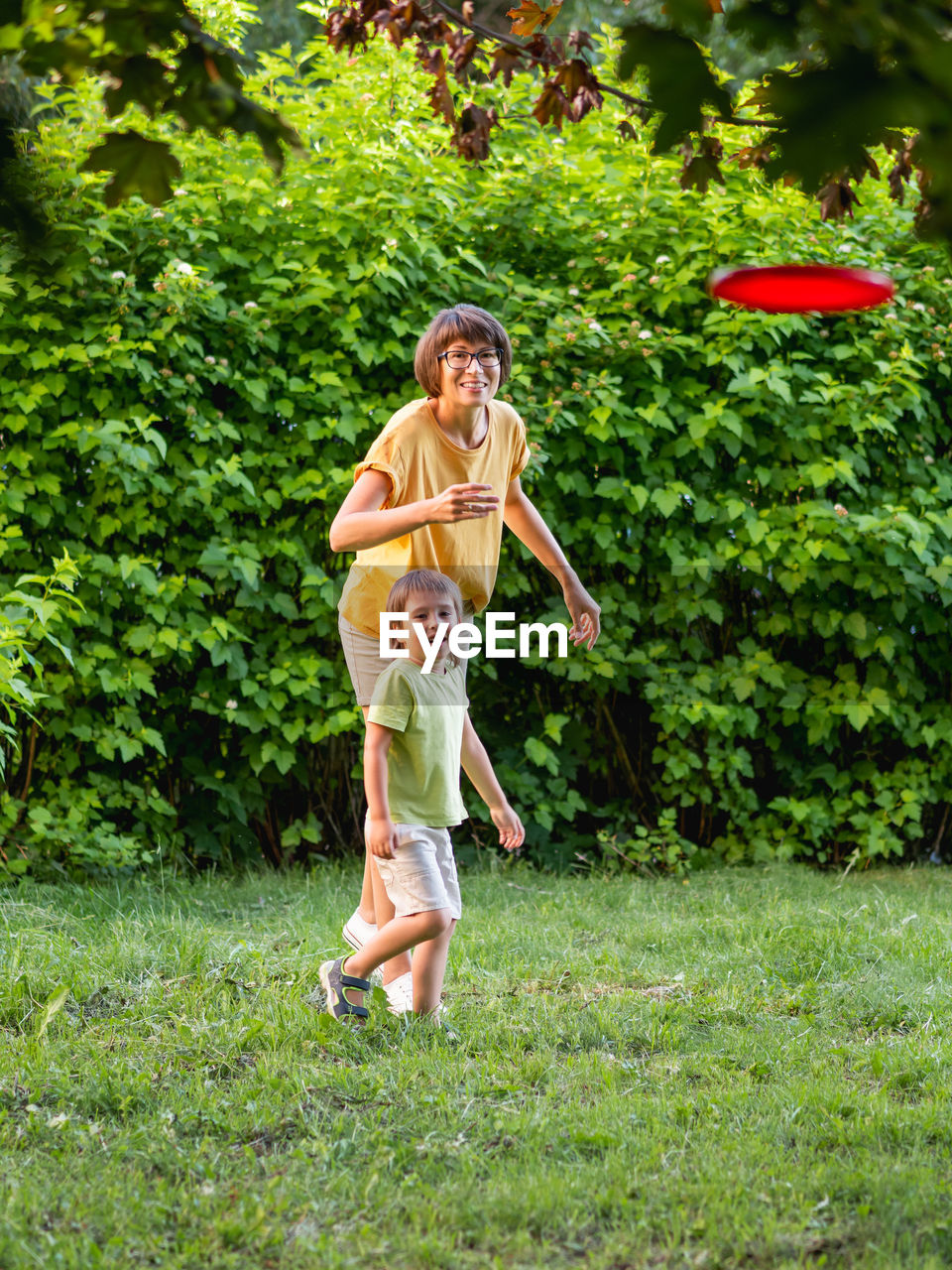 Mother and son play frisbee on grass lawn. summer vibes. outdoor leisure activity. 