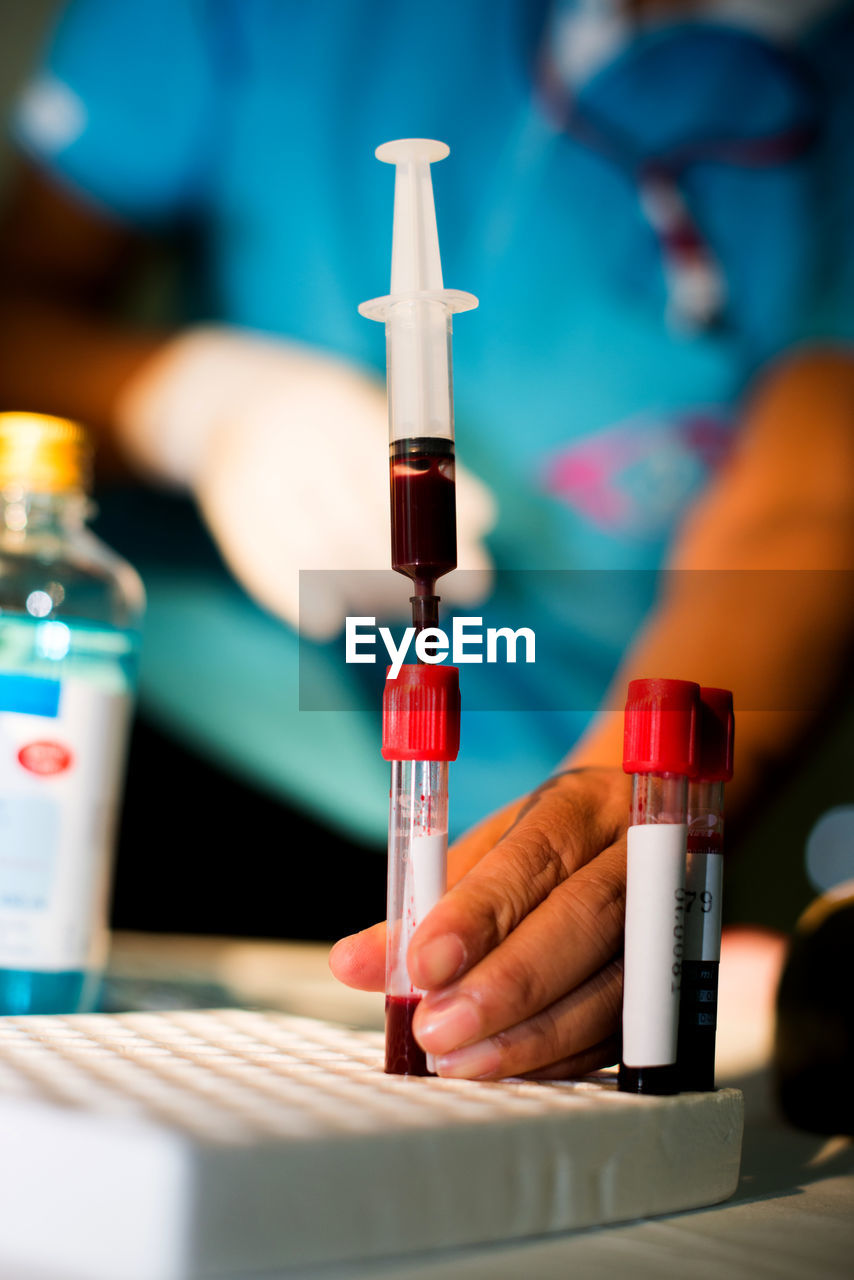 Midsection of doctor examining blood sample in test tube