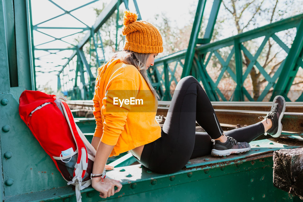 Woman trekking rests on an abandoned old railway bridge