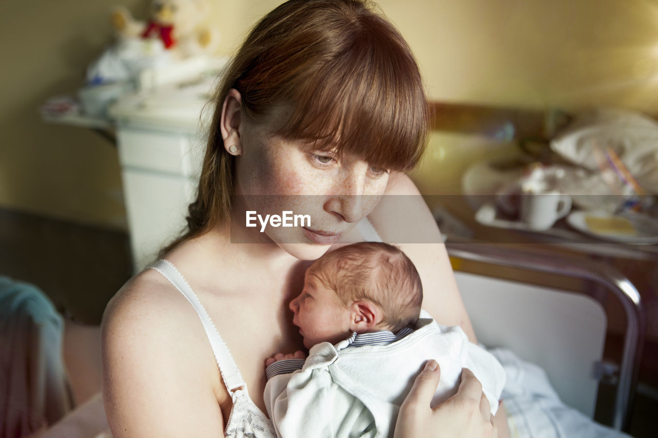 Mother holding her newborn baby in hospital room