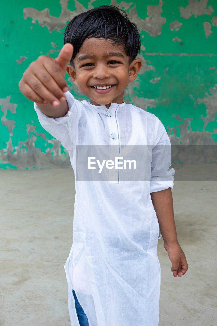 PORTRAIT OF BOY STANDING AGAINST WALL