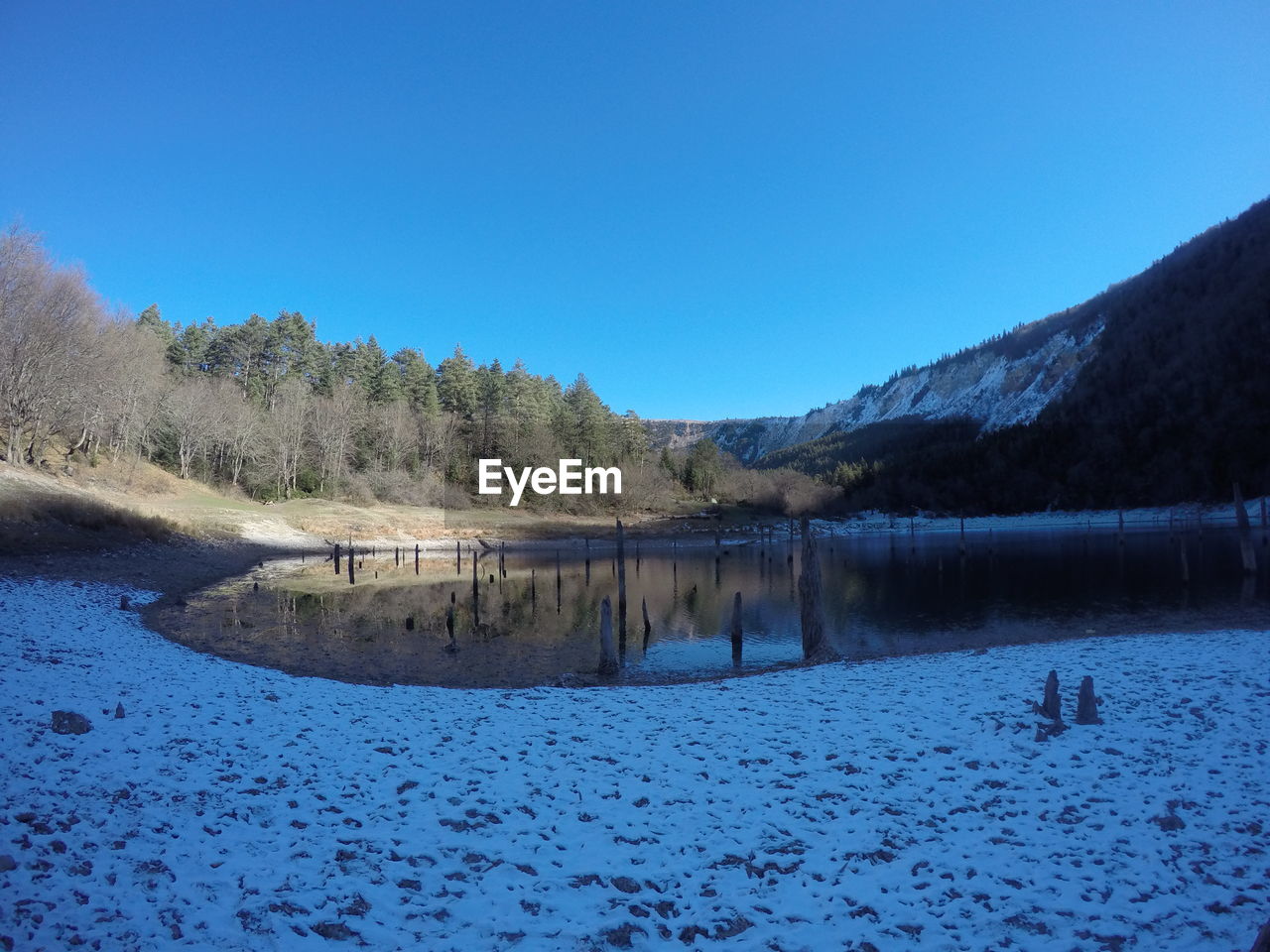 Scenic view of lake against clear blue sky