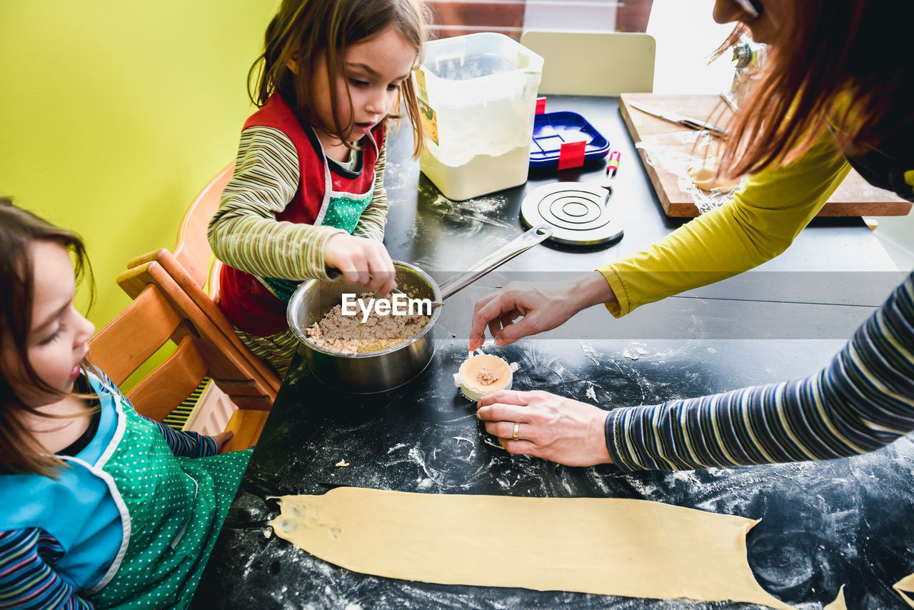 High angle view of mother with daughters preparing food in kitchen