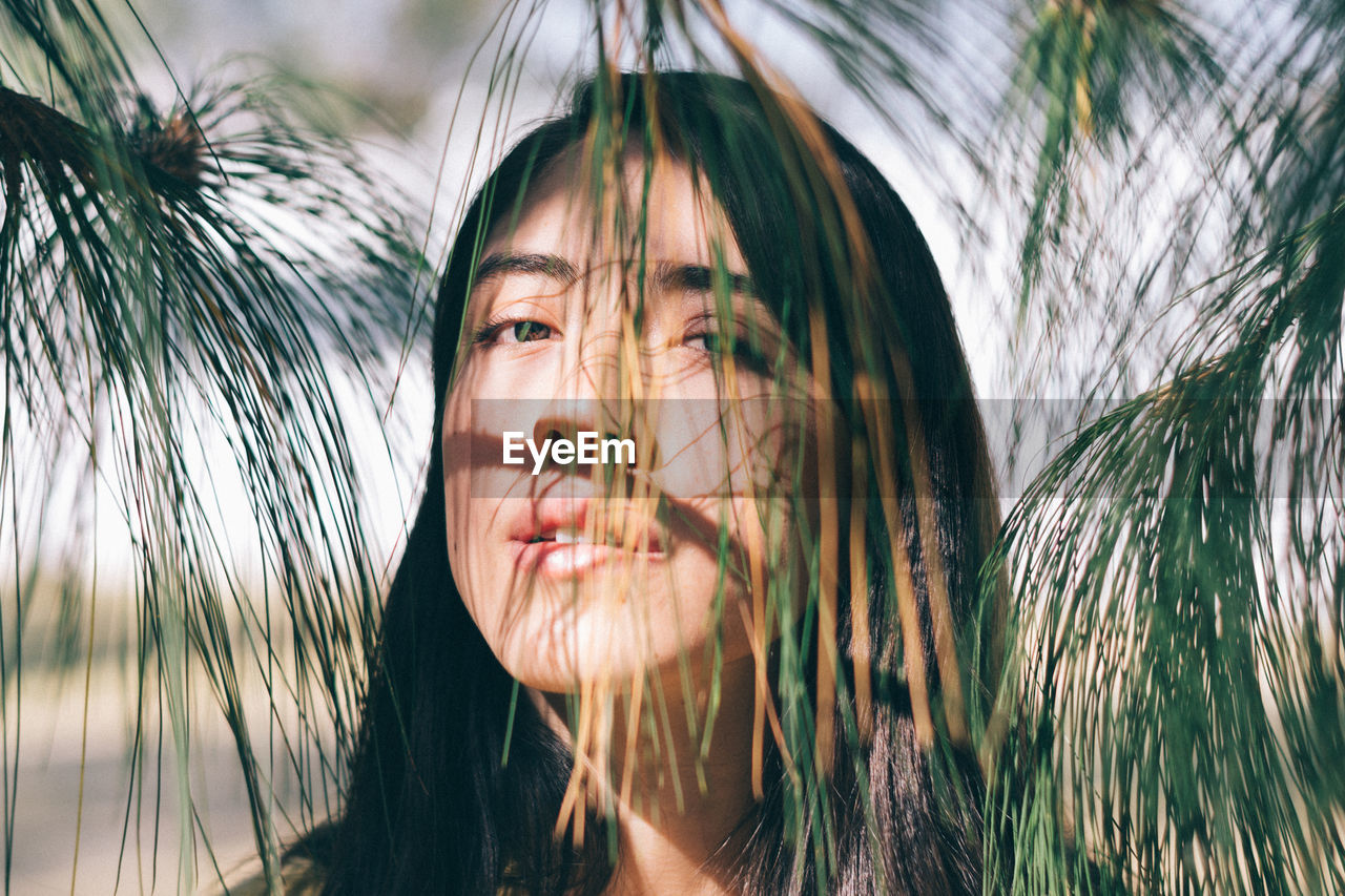 Close-up portrait of young woman seen from twigs